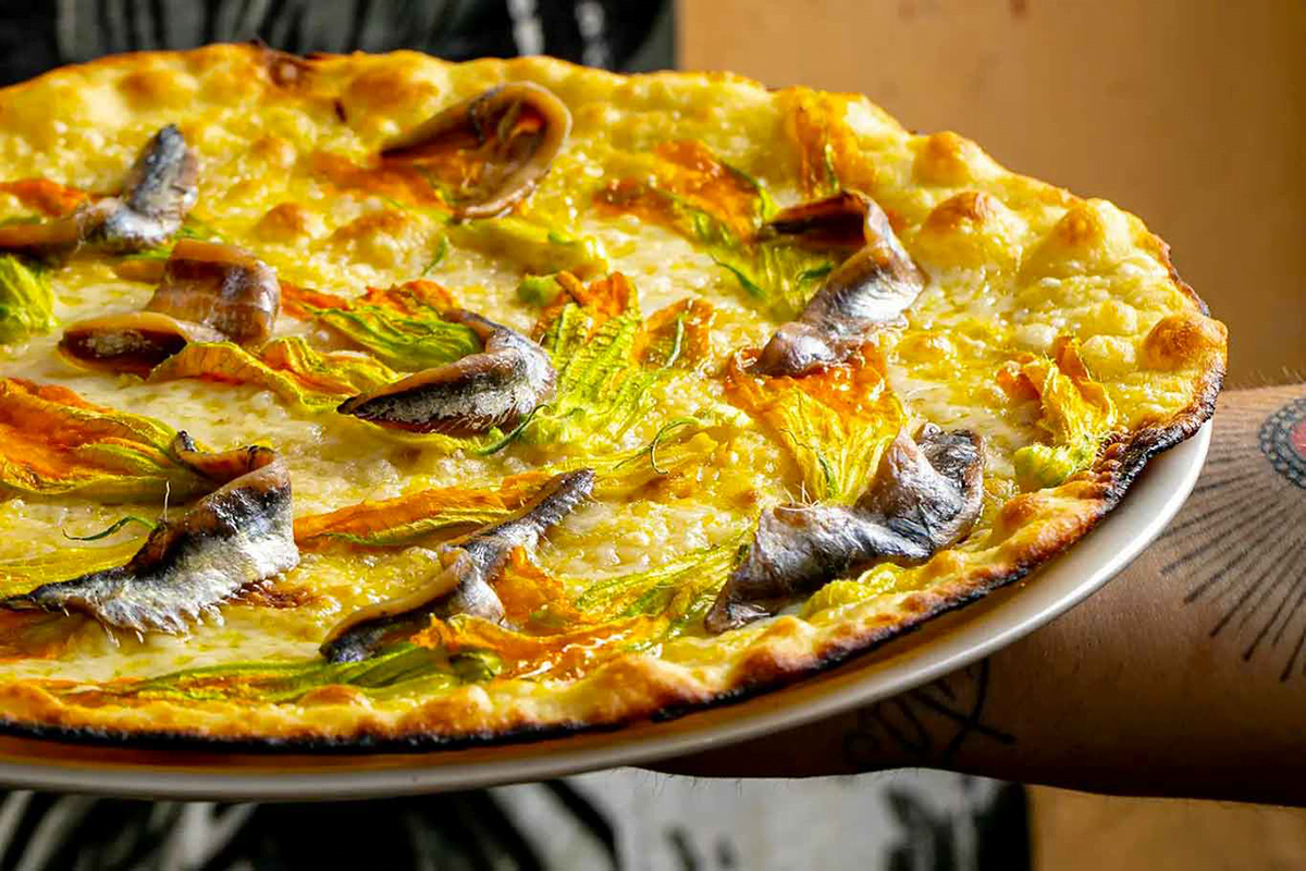 Roman pizza tonda with anchovies and zucchini flowers on top