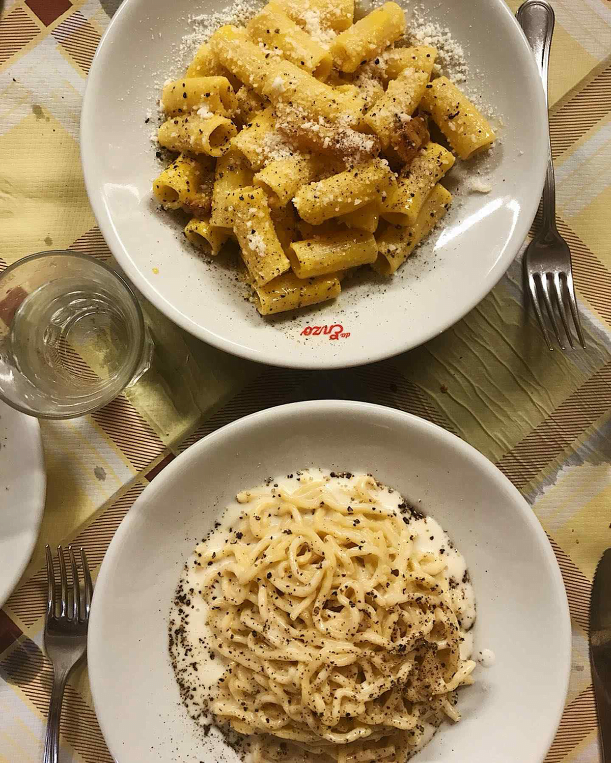 Plates of Da Enzo's carbonara and cacio e pepe on a table